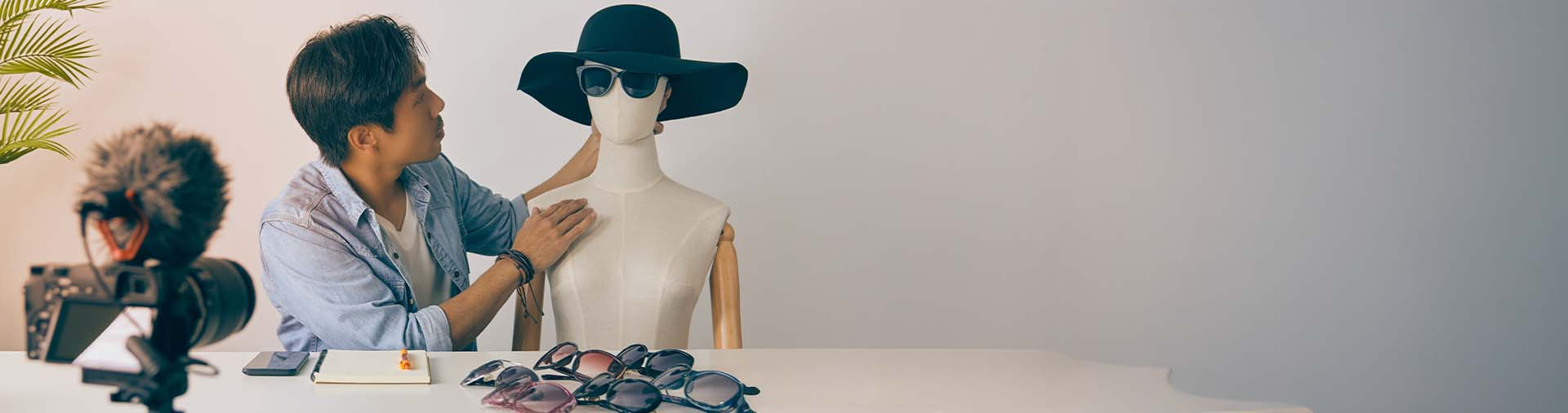 Blogueur asiatique mettant des lunettes de mode sur le visage des mannequins et enregistrant une vidéo.